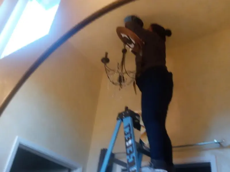 Electrician installing a chandelier in a Big Spring residence